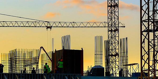 Grues à tour et la silhouette du bâtiment avec les travailleurs au coucher du soleil