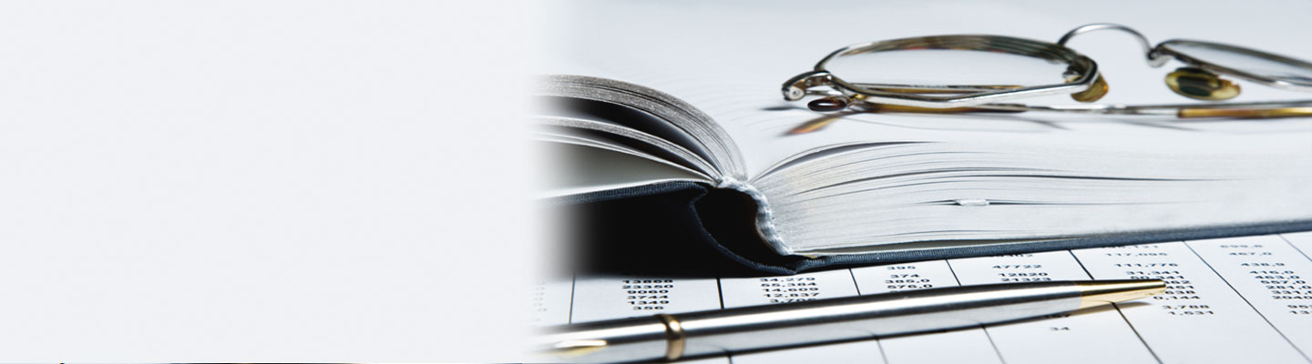 Lunettes pliées sur un livre ouvert; crayon déposé sur une grille budgétaire